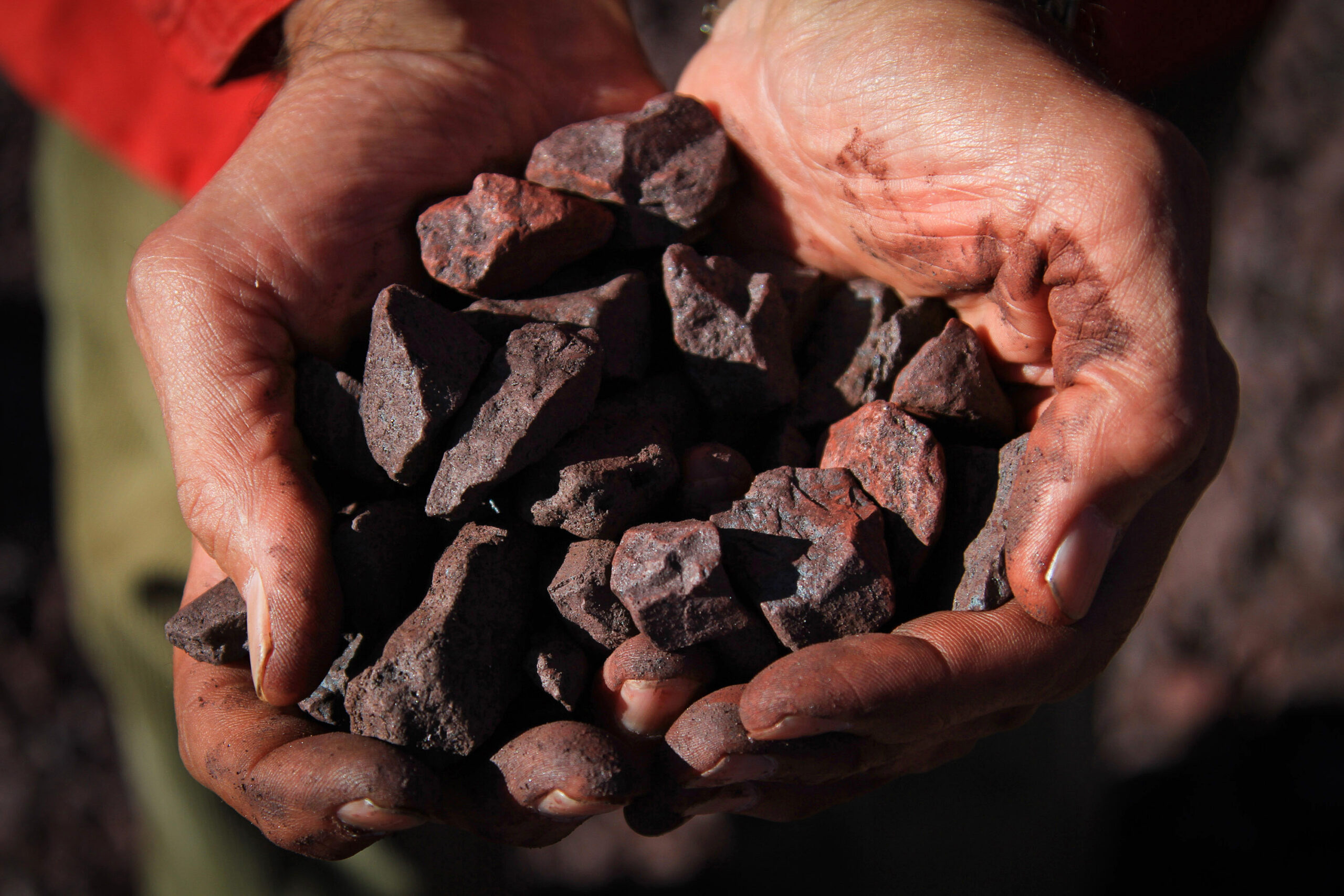 An employee displays iron ore in this arranged photograph at the Sishen mine, operated by Kumba Iron Ore Ltd., an iron ore-producing unit of Anglo American Plc, in Shishen, South Africa, on Wednesday, Aug. 24, 2011. Kumba Iron Ore Ltd. may decide on the next stage of its Sishen-Saldanha expansion in 2014, the company said in a presentation on its website today. Photographer: Nadine Hutton/Bloomberg